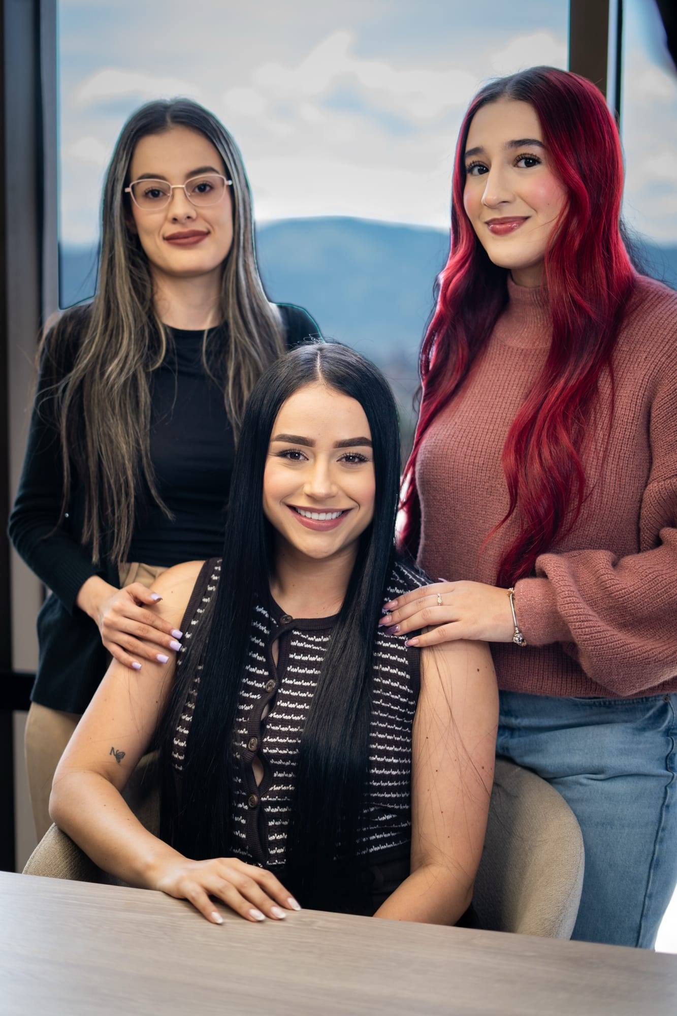 Tres integrantes del equipo de Solvé Abogados sonriendo en la oficina, con vista a las montañas