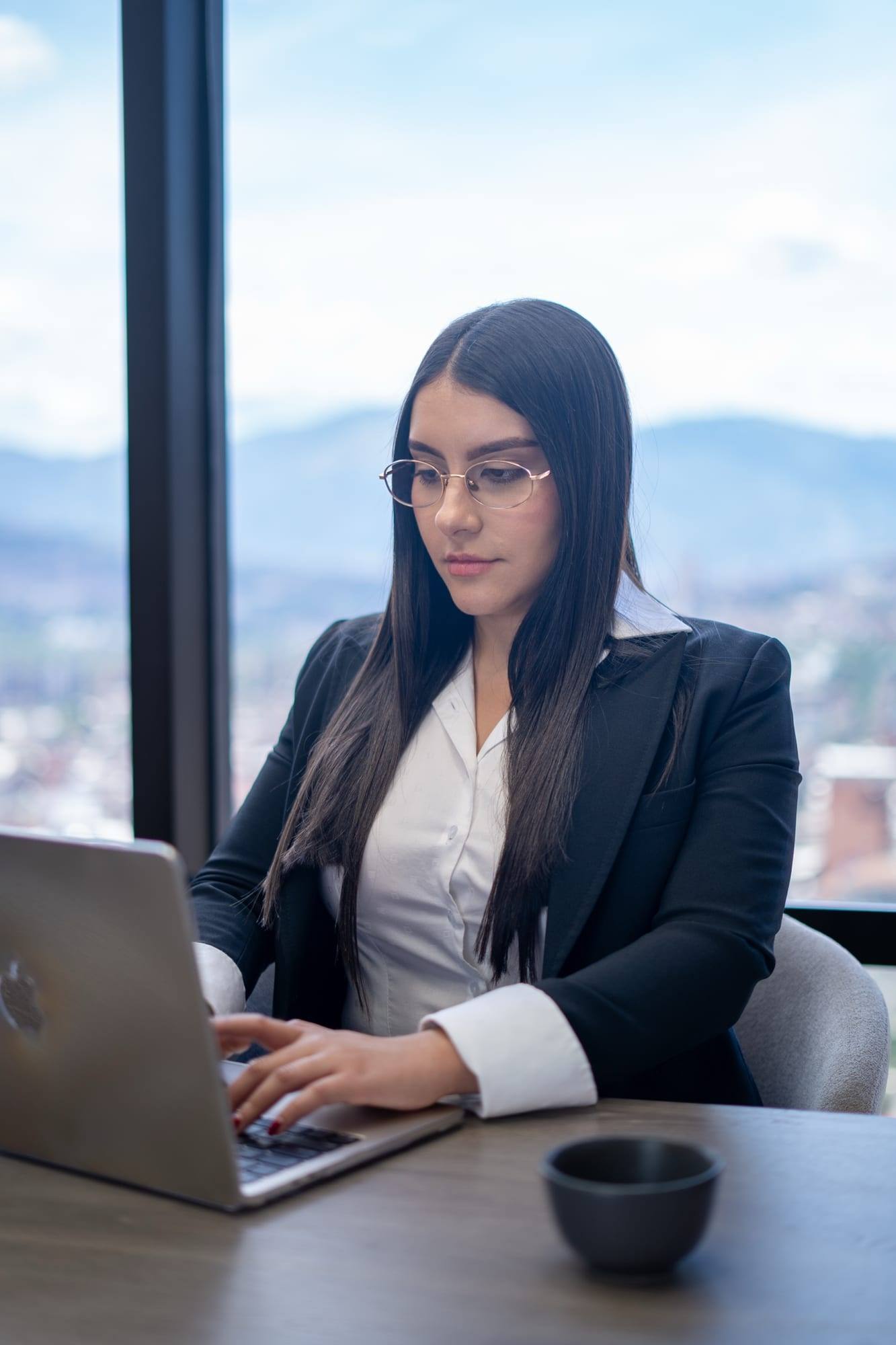 Integrante del equipo de Solvé Abogados trabajando en su portátil junto al ventanal