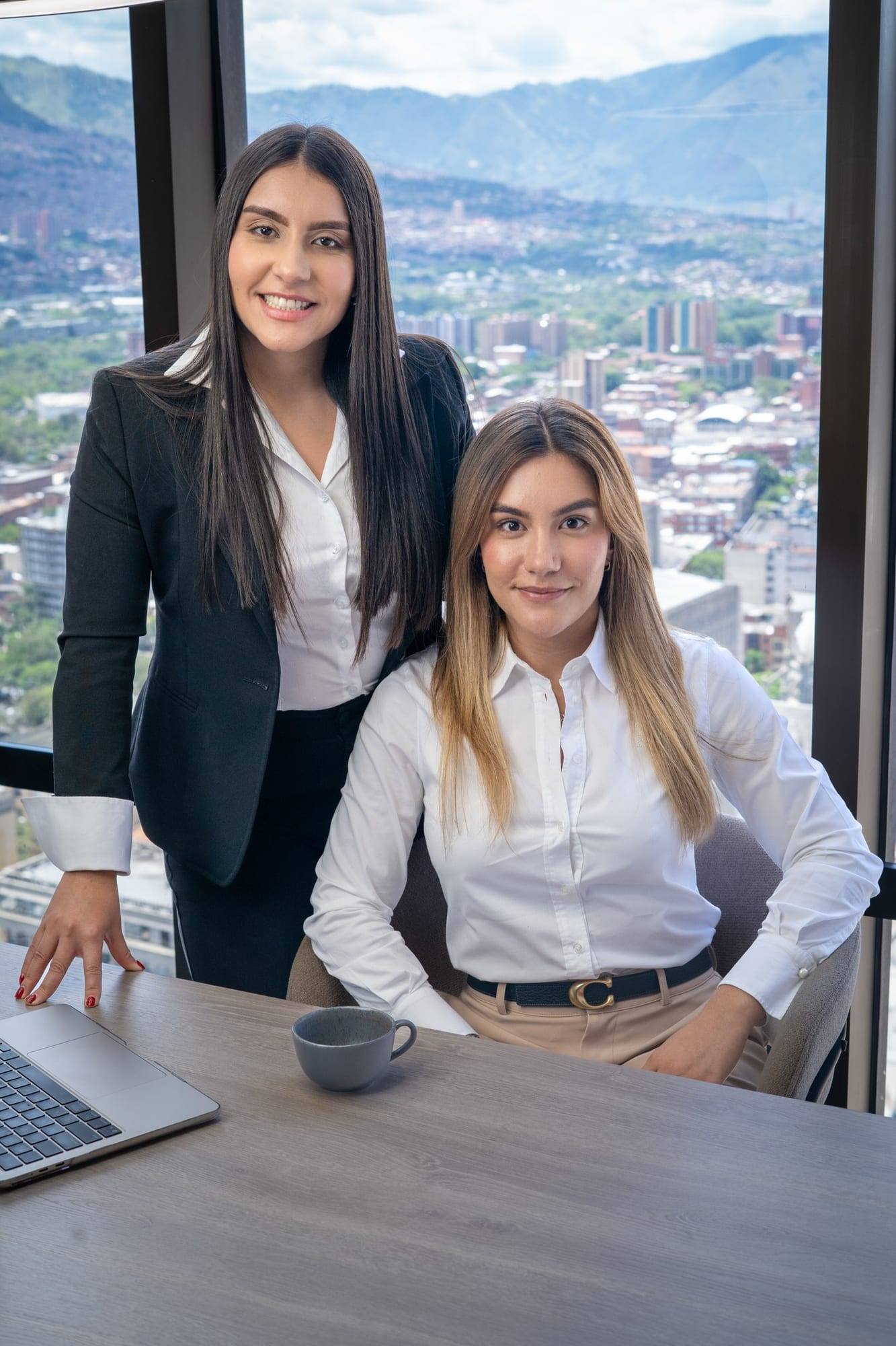 Dos integrantes del equipo de Solvé Abogados en la oficina, junto a un ventanal con vista a la ciudad